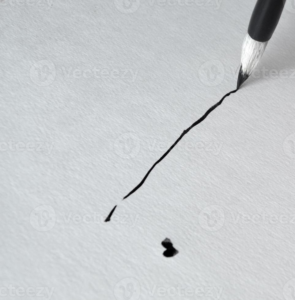 Die Linie wird mit schwarzer Tinte und einem Pinsel für Kalligrafie gezeichnet foto