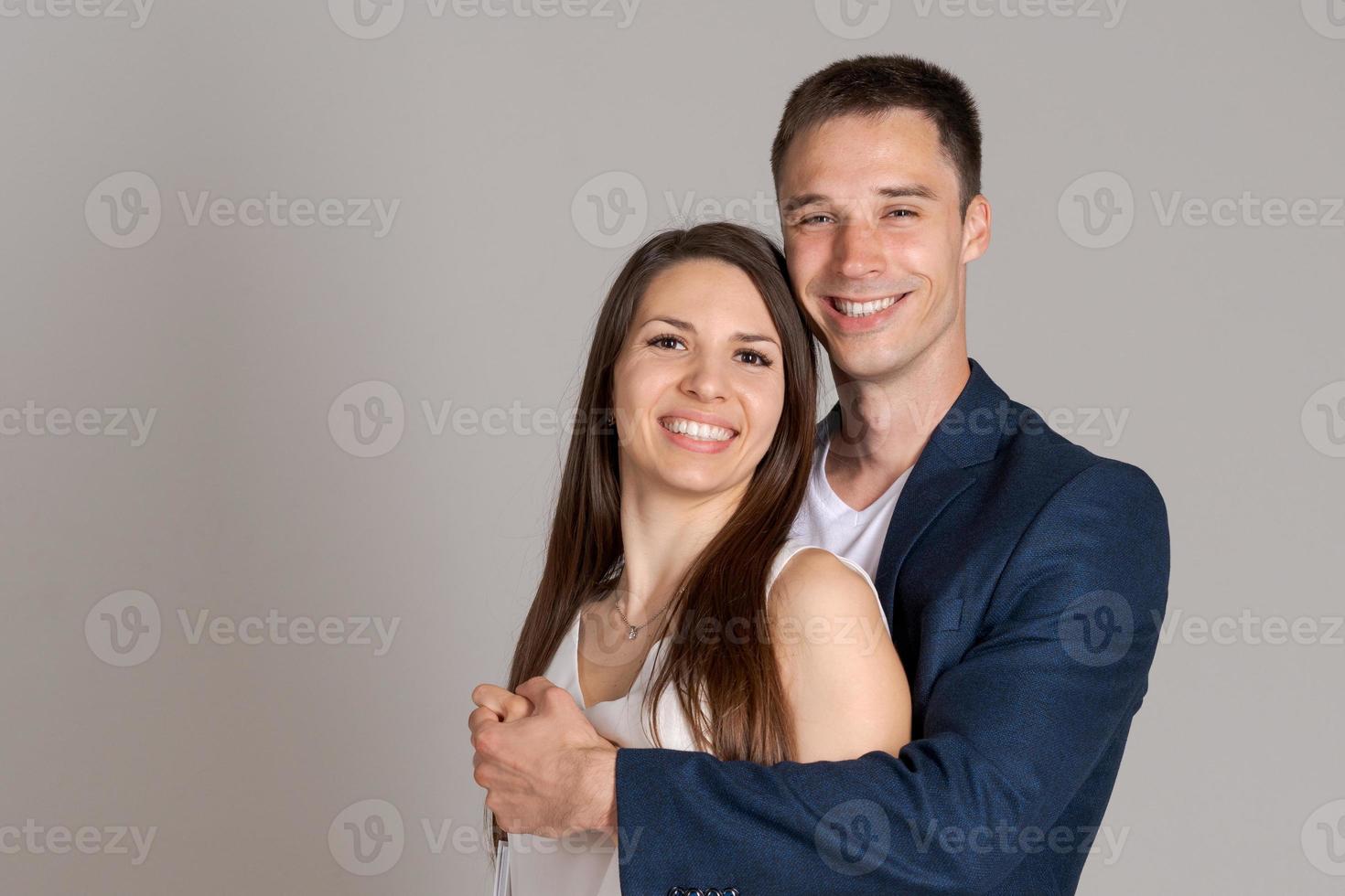 Glücklicher Kaukasier umarmt seine Freundin auf grauem Hintergrund. beruflich erfolgreich foto