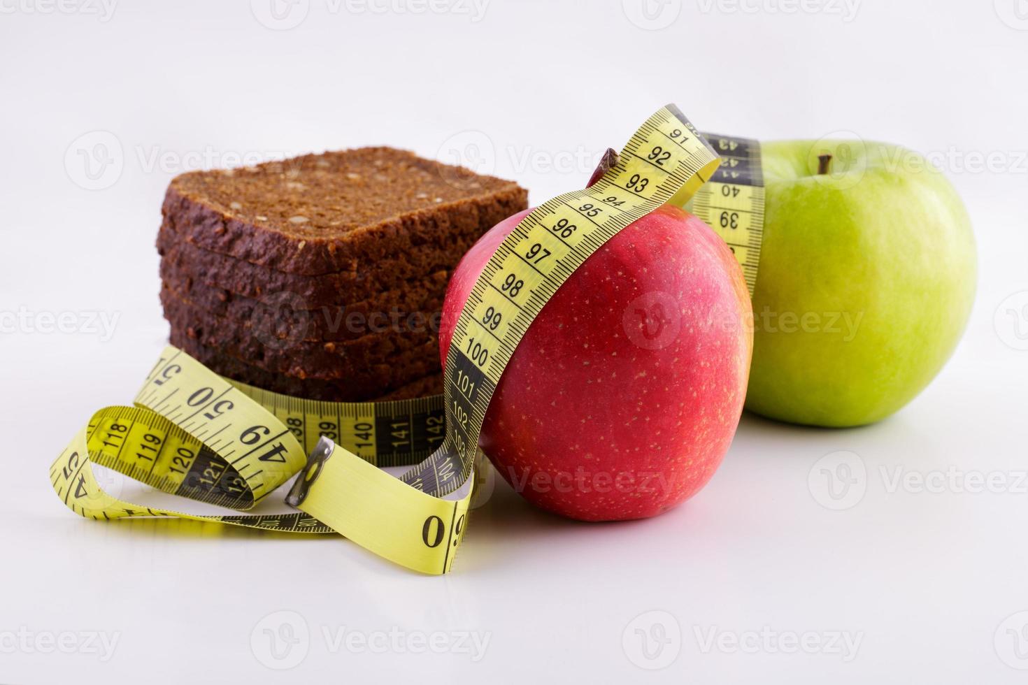 Schwarzbrot und Äpfel auf weißem Hintergrund mit Maßband foto