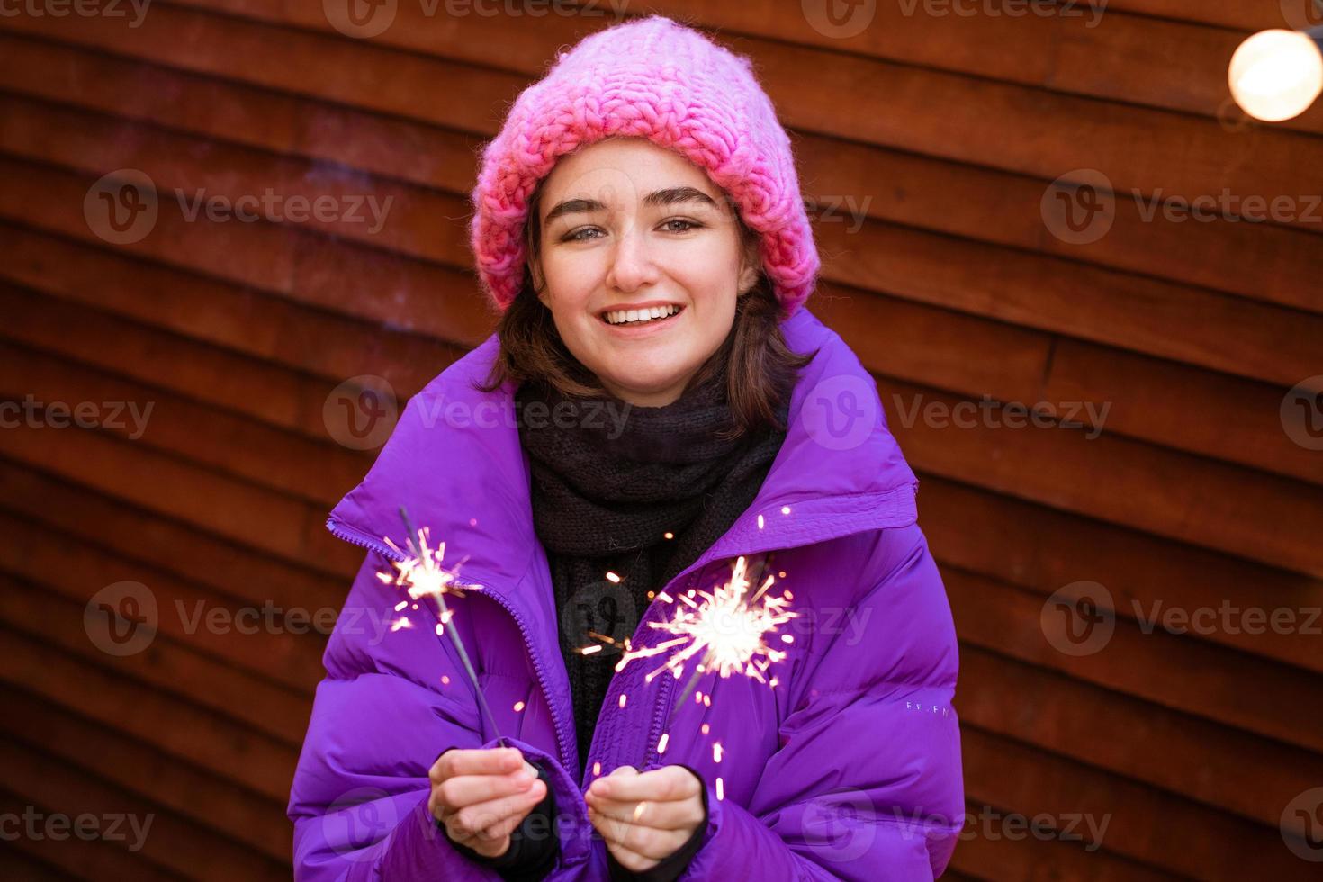 Kaukasisches Mädchen hat Spaß im Winter auf der Straße mit Wunderkerzen in der Hand foto