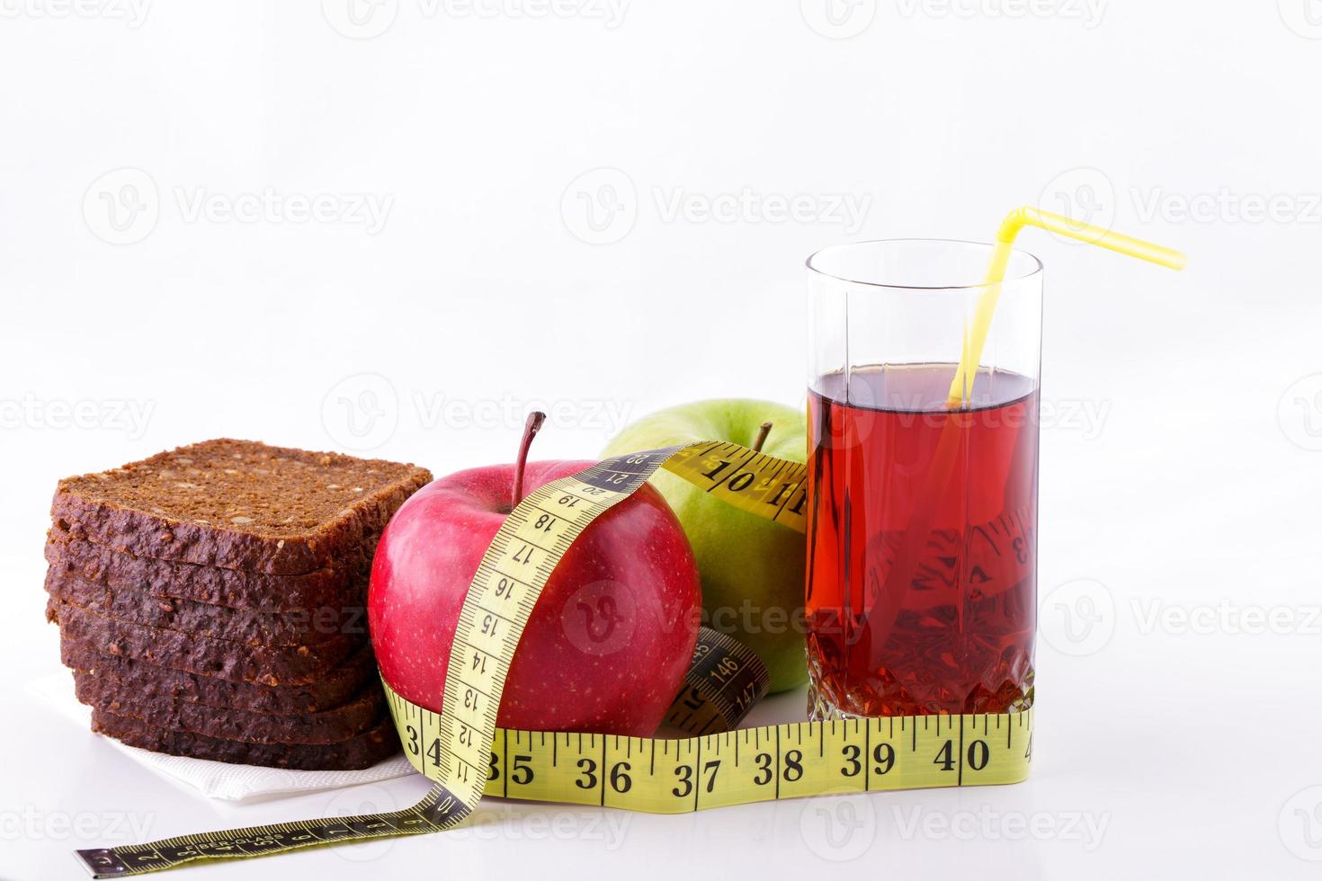 Roggenbrotäpfel und Saft im Glas auf weißem Hintergrund mit einem Maßband foto