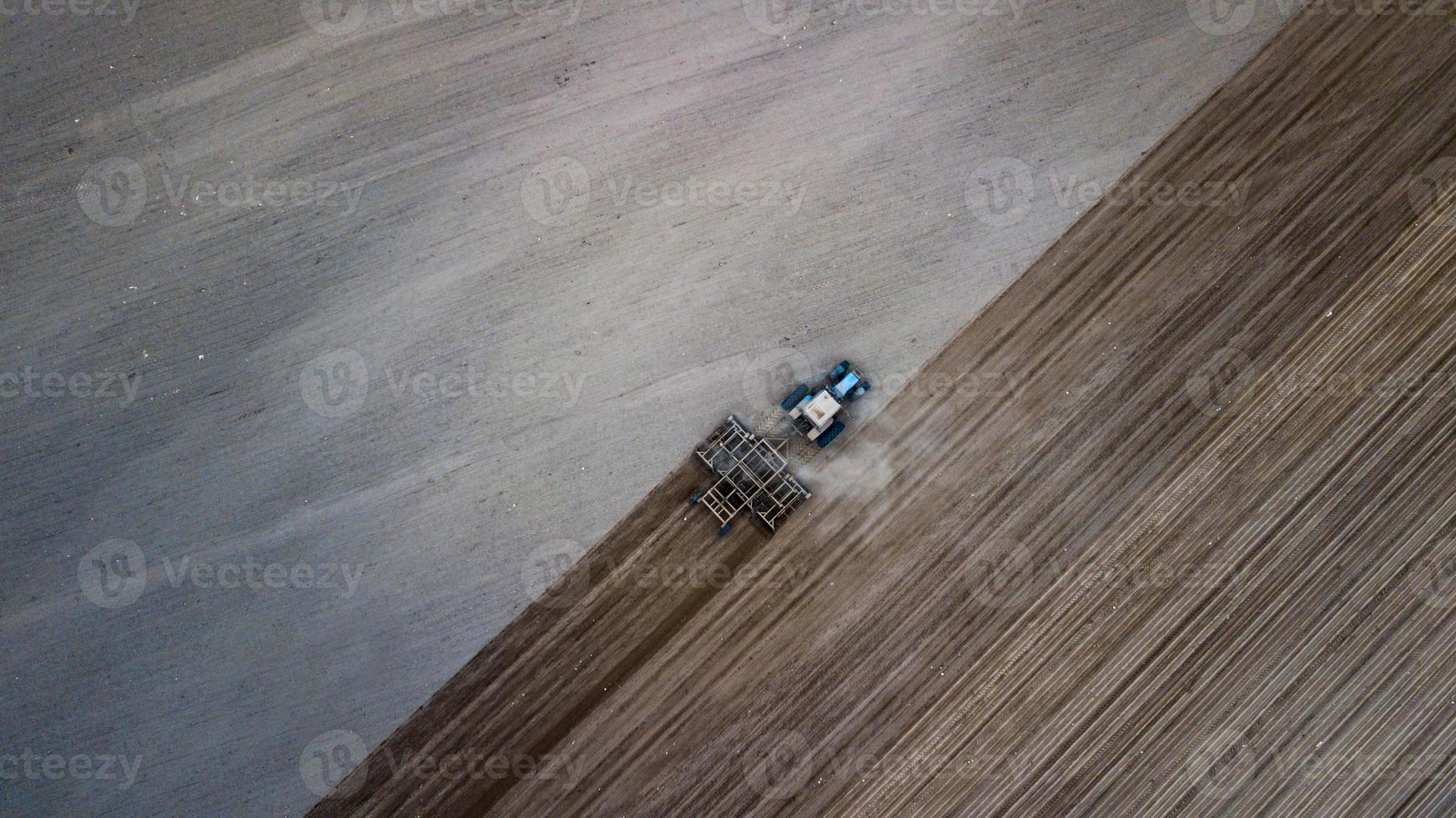 Luftaufnahme eines Traktors, Mähdrescher, der im Frühjahr landwirtschaftliche Flächen pflügt foto