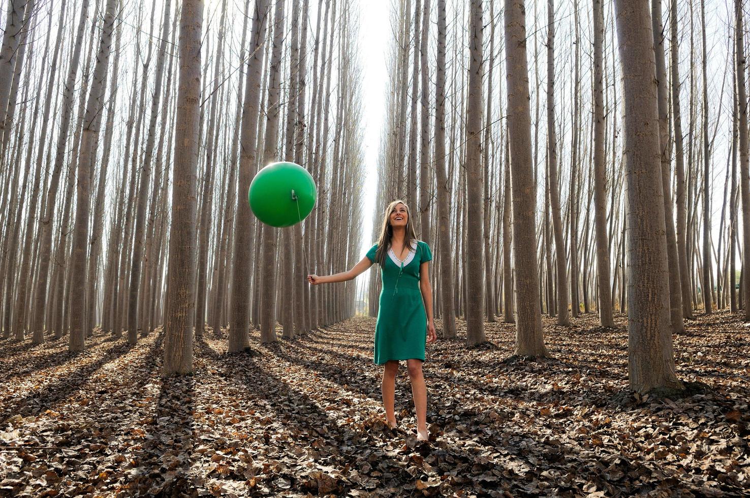 Schönes blondes Mädchen, grün gekleidet, geht in den Wald foto