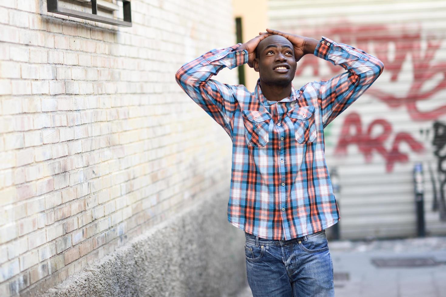schwarzer Mann, der Freizeitkleidung im städtischen Hintergrund trägt foto