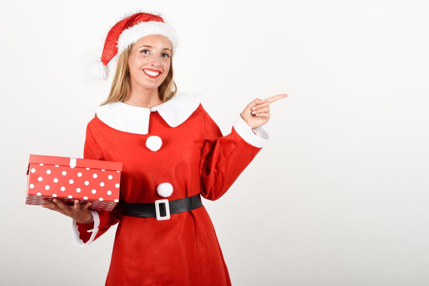 blonde frau in weihnachtsmannkleidung, die mit geschenkbox lächelt. foto