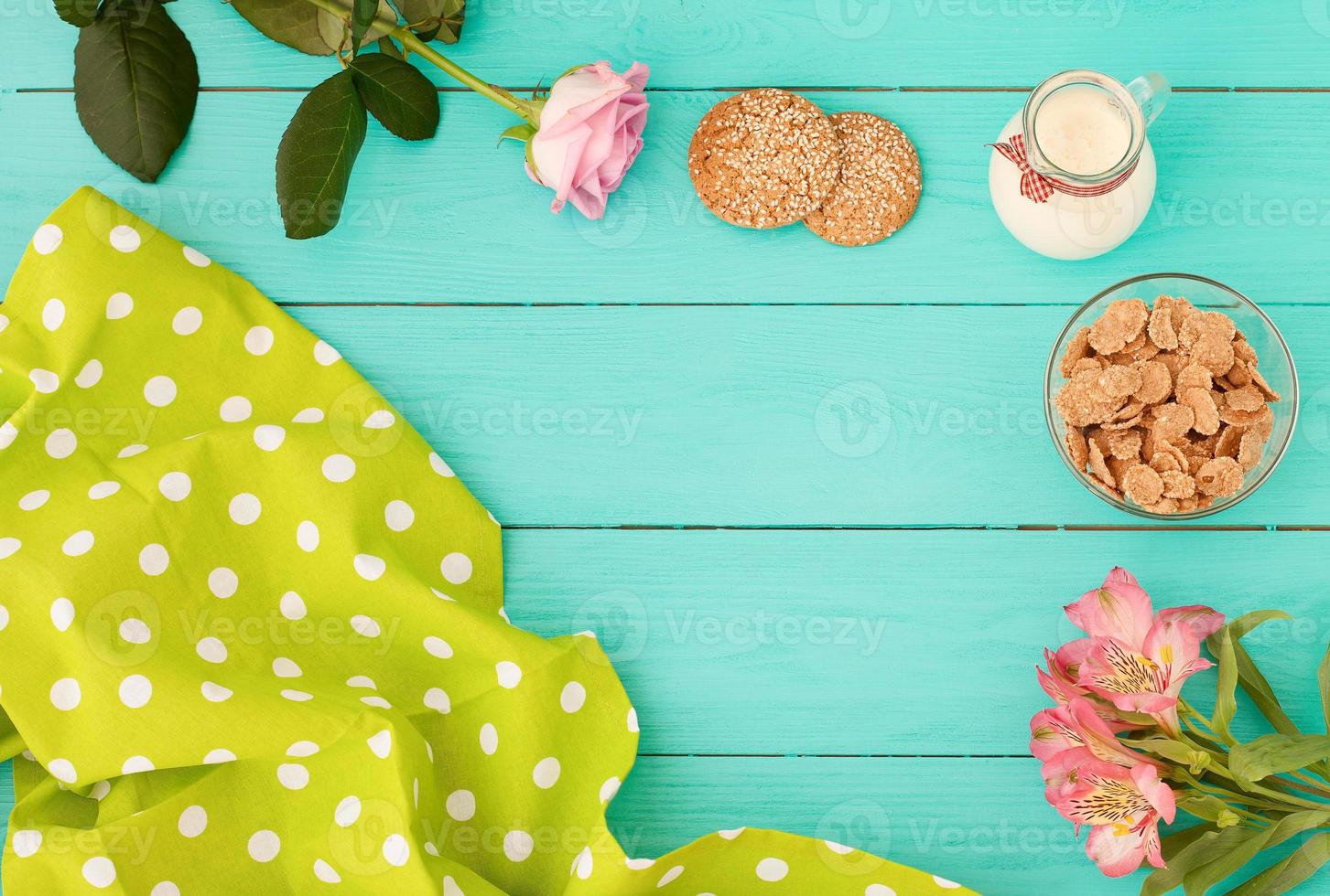 rahmen des morgendlichen essens mit krug milch, keksen und haferflocken auf blauem holzhintergrund. Tischdecke mit Tupfen und Blumen. Ansicht von oben. Attrappe, Lehrmodell, Simulation. Platz kopieren foto