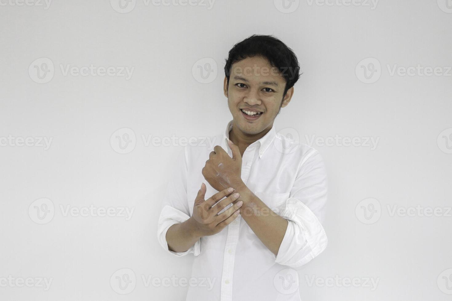 asiatischer hübscher junger mann, der creme an seiner hand mit smileygesicht aufträgt, hautpflegekonzept, lokalisiert auf weißem hintergrund foto