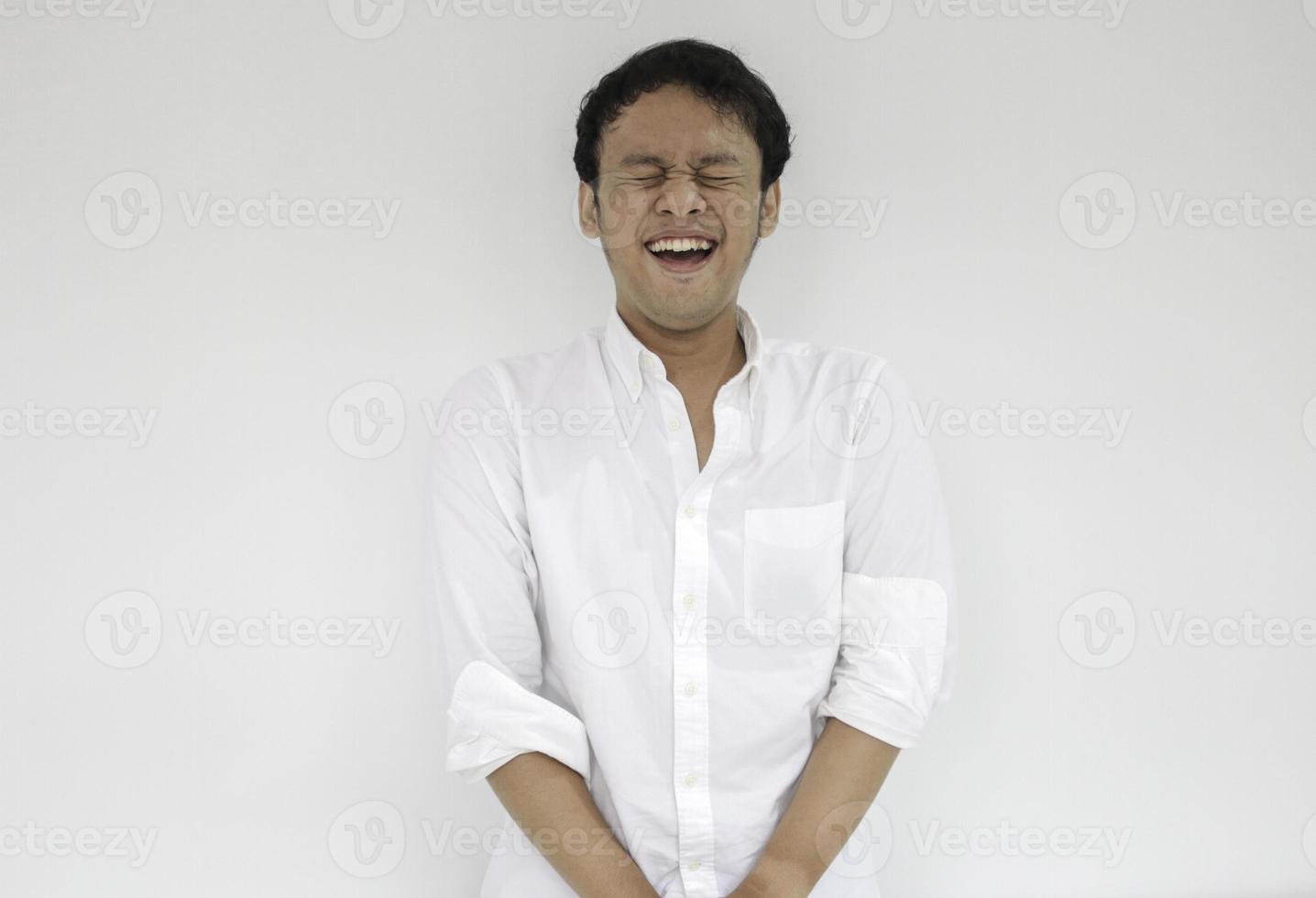 Porträt eines jungen lustigen asiatischen Mannes mit weißem Hemd, der in die Kamera blickt und einen glücklichen Ausdruck lächelt foto