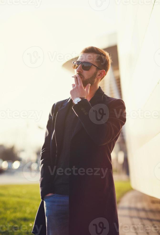 mann in einem mantel und g raucht eine zigarette foto