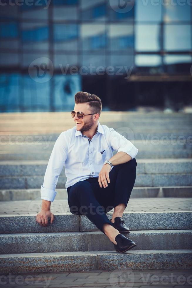 Mann mit einem Lächeln, der auf der Treppe sitzt foto