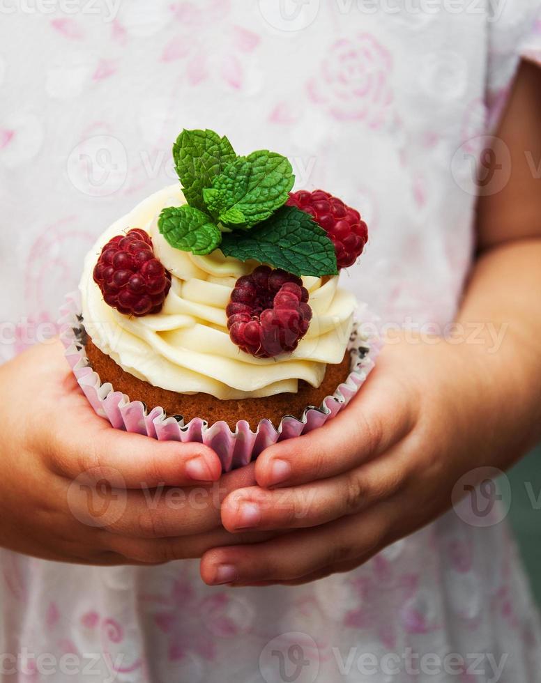 kleines Mädchen, das kleinen Kuchen hält foto