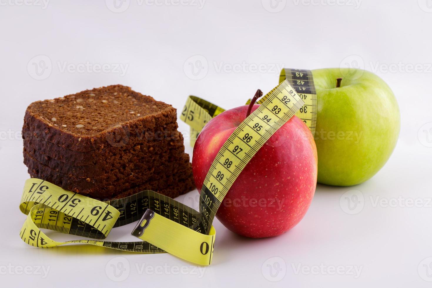 Schwarzbrot und Äpfel auf weißem Hintergrund mit Maßband foto