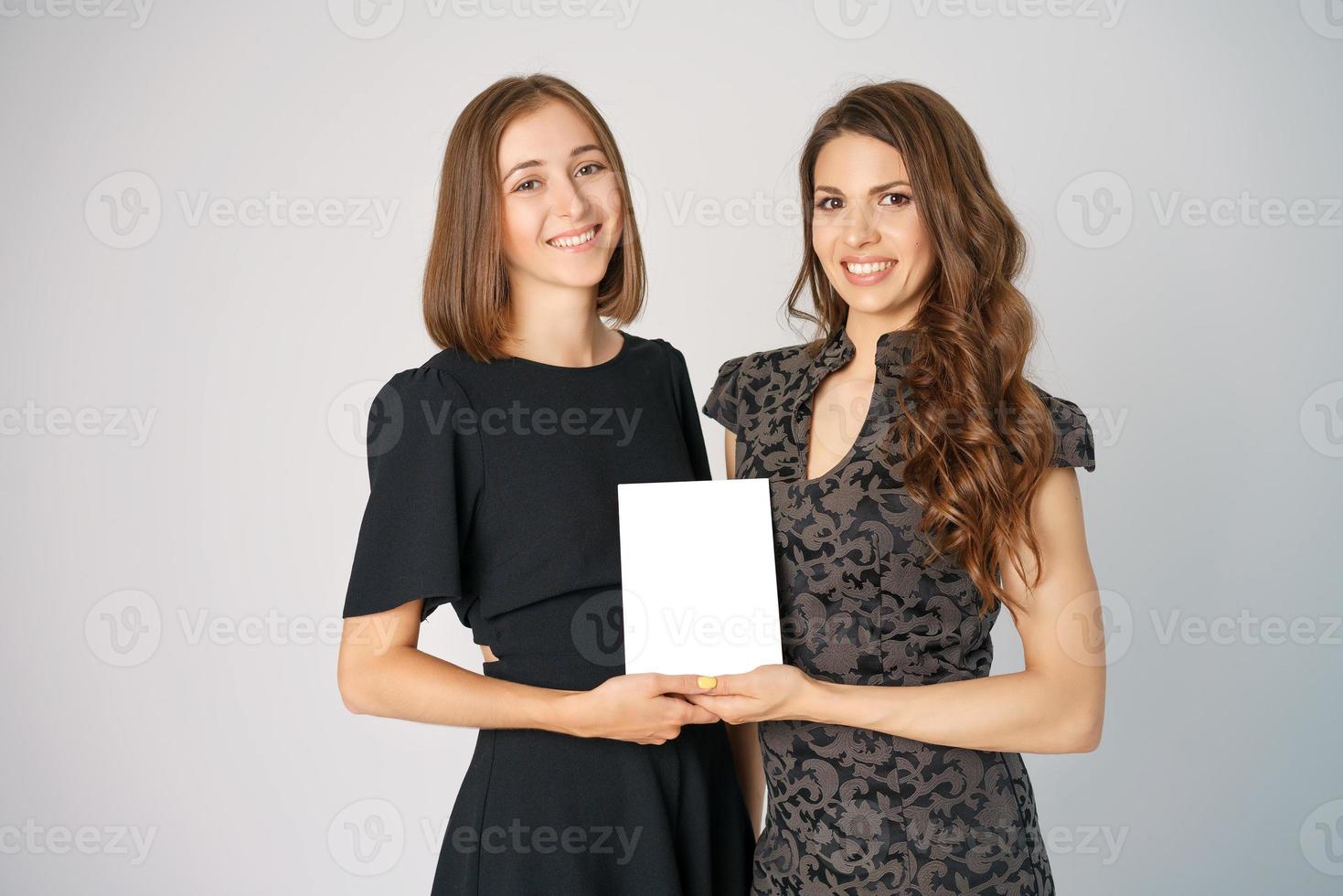 zwei glückliche junge frauen, die ein modell im hintergrund halten foto