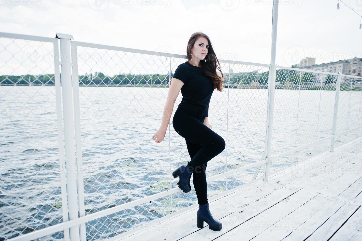 junges Mädchen in schwarzer Kleidung posierte auf dem Pier foto