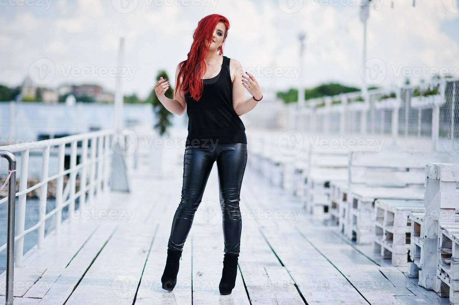 Junges rothaariges Mädchen in schwarzer Kleidung posierte auf dem Pier foto