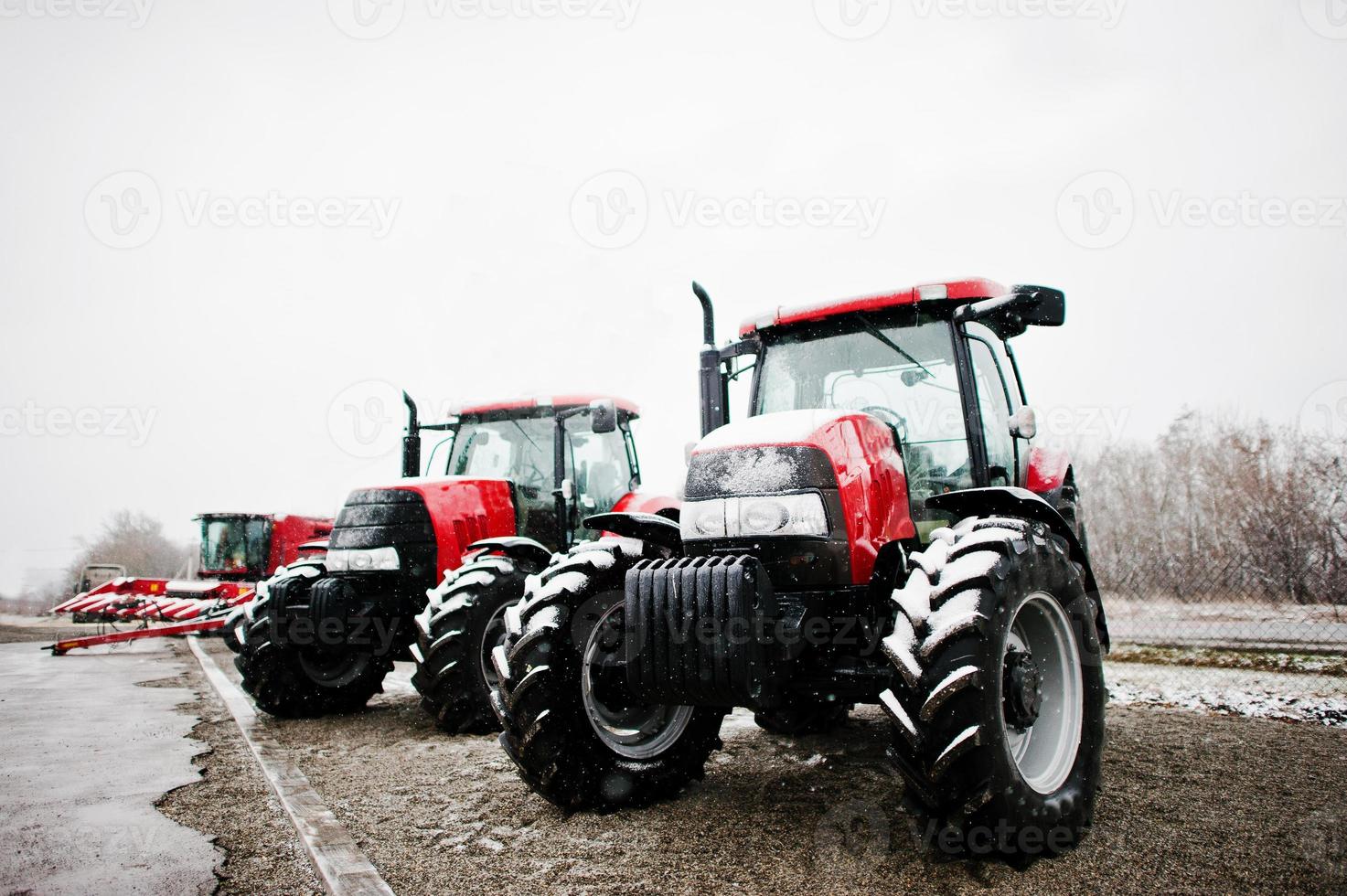 Zwei neue rote Traktoren bleiben bei verschneitem Wetterhintergrund combaine foto
