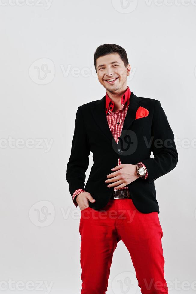 Mode lachender junger Mann im schwarzen Anzug und rote Hose beiläufige Posen im Studio foto