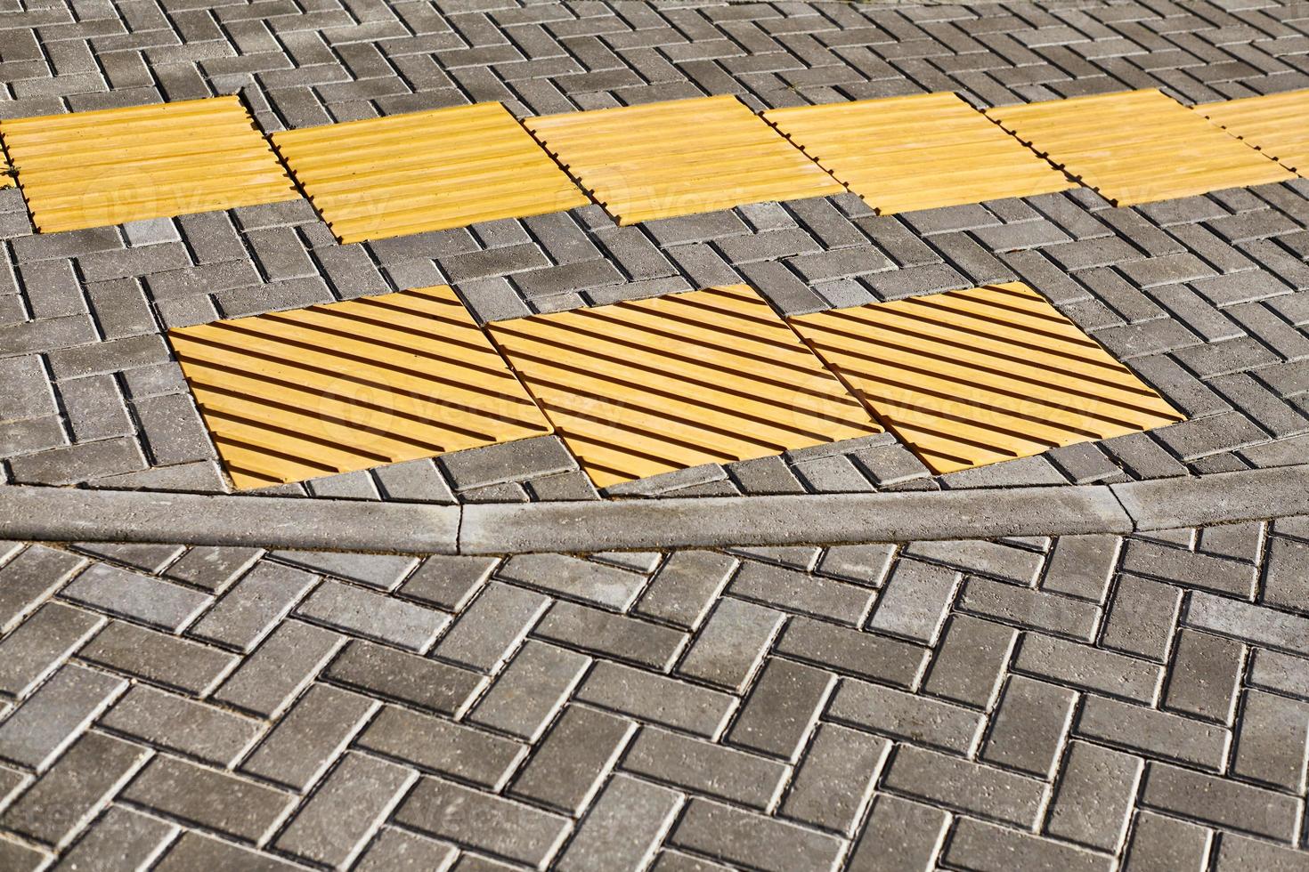 gelbes taktiles Pflaster auf Gehweg, taktile Bodenoberflächenindikatoren für Blinde und Sehbehinderte foto