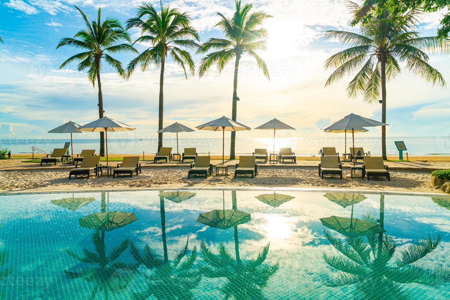 Wunderschöner Luxus-Sonnenschirm und -Stuhl um den Außenpool im Hotel und Resort mit Kokospalme bei Sonnenuntergang oder Sonnenaufgang foto