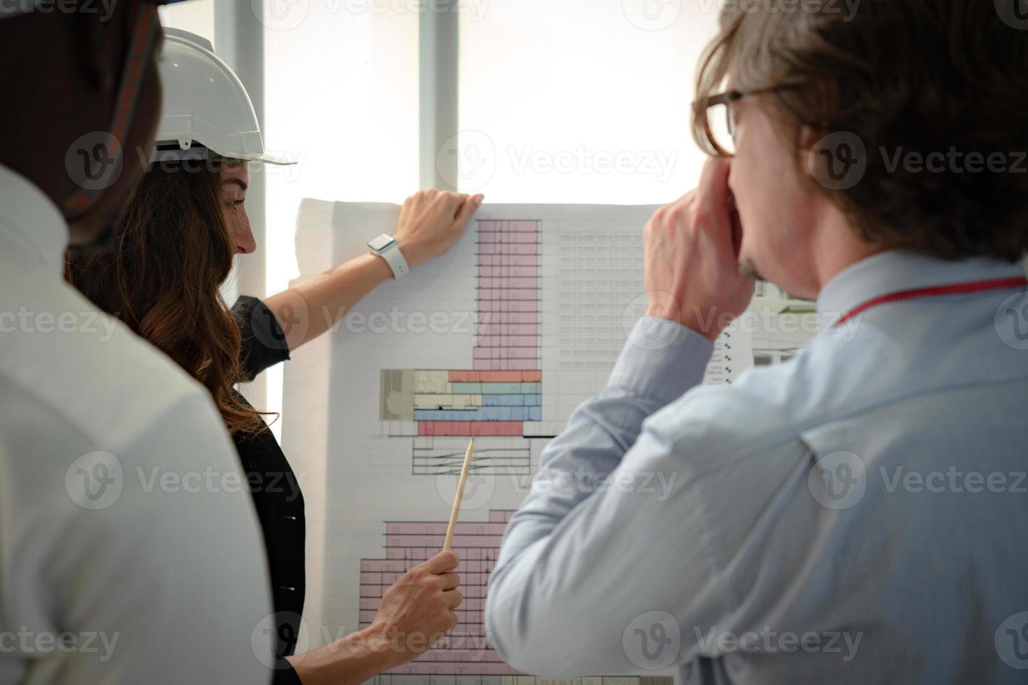 Junger Architekt, der dem Manager und dem Kunden bei einem Treffen den Grundriss des Gebäudes vorlegt foto