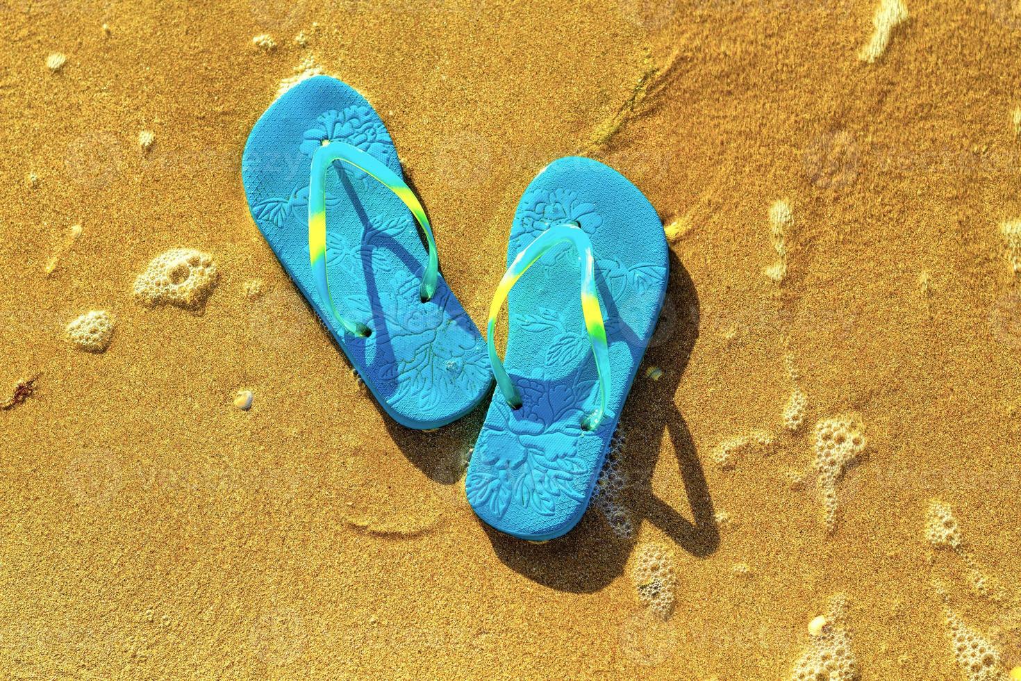 blaue Sandalen am Strand, das Konzept der Ruhe am Meer foto