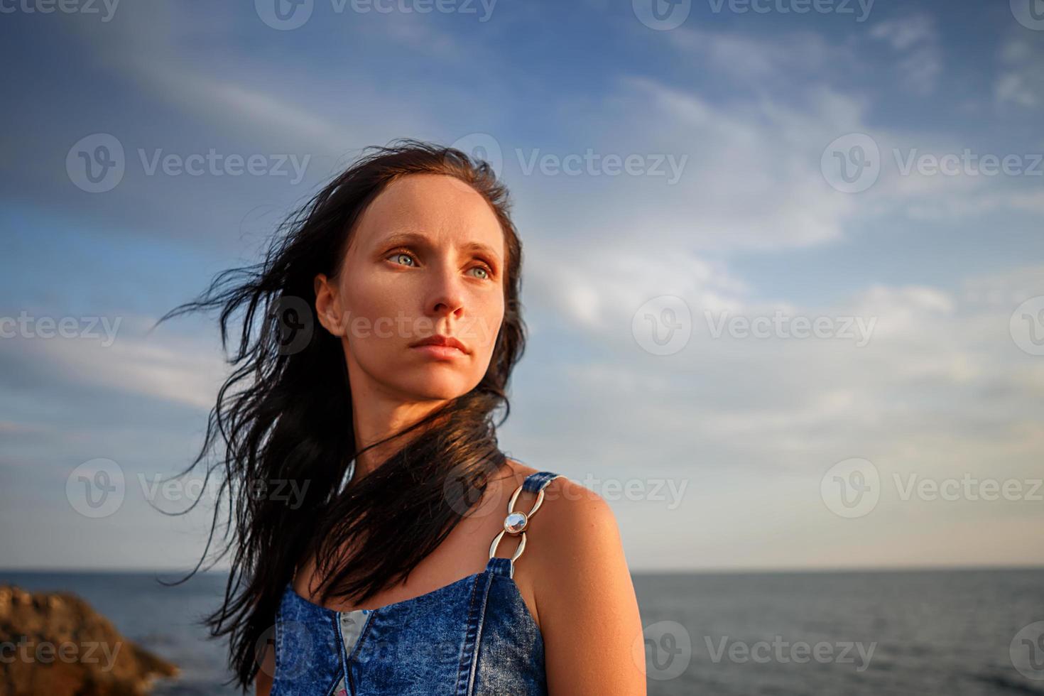 schöne Frau, die bei Sonnenuntergang gegen den Himmel in die Ferne blickt foto