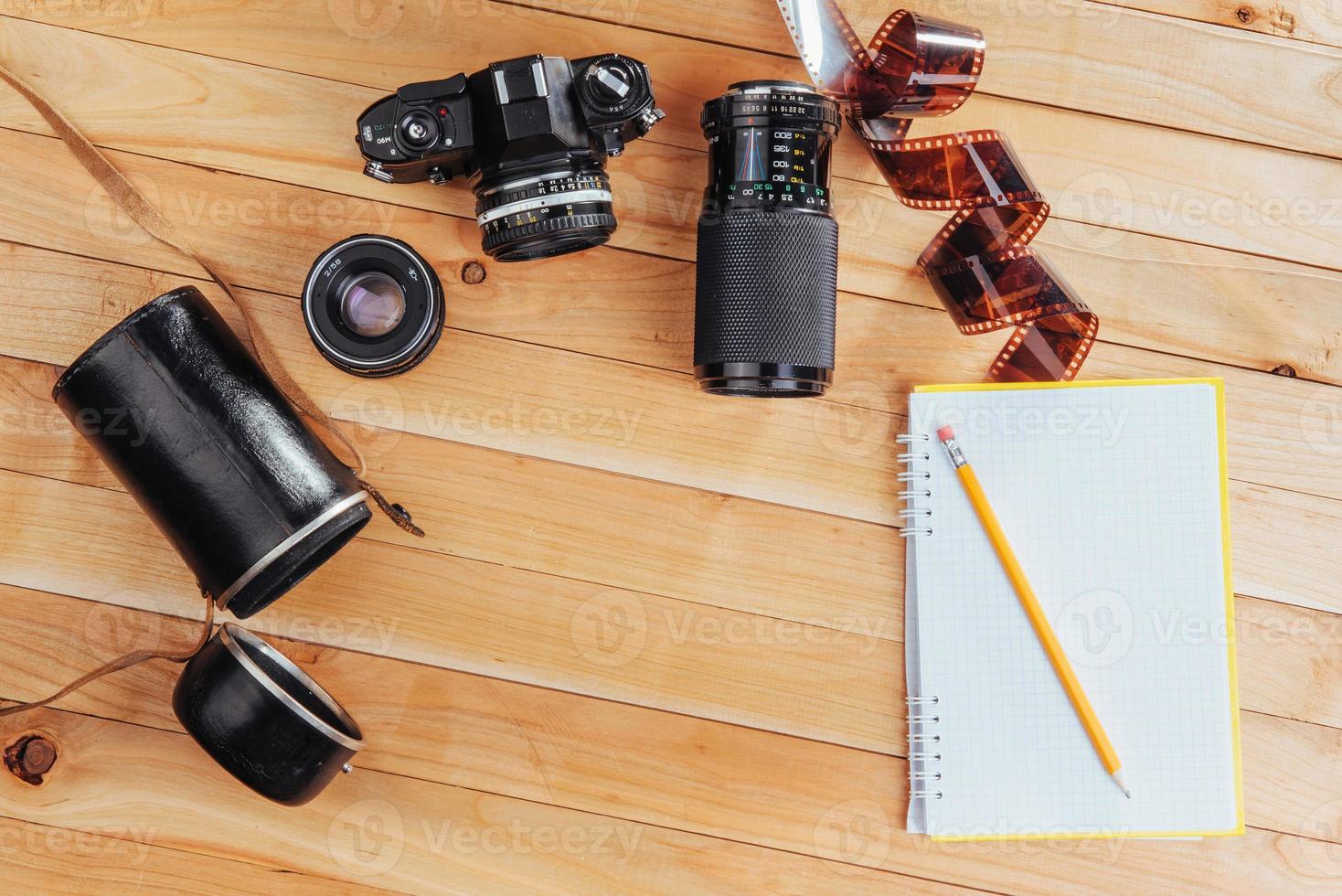 die alte filmkamera und rollfilm und notizbuch mit bleistift auf einem hölzernen hintergrund foto