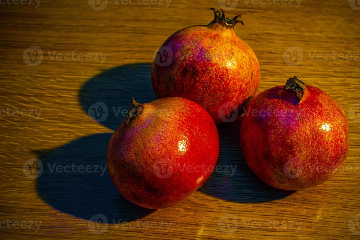 drei reife Granatäpfel auf dem Holztisch foto