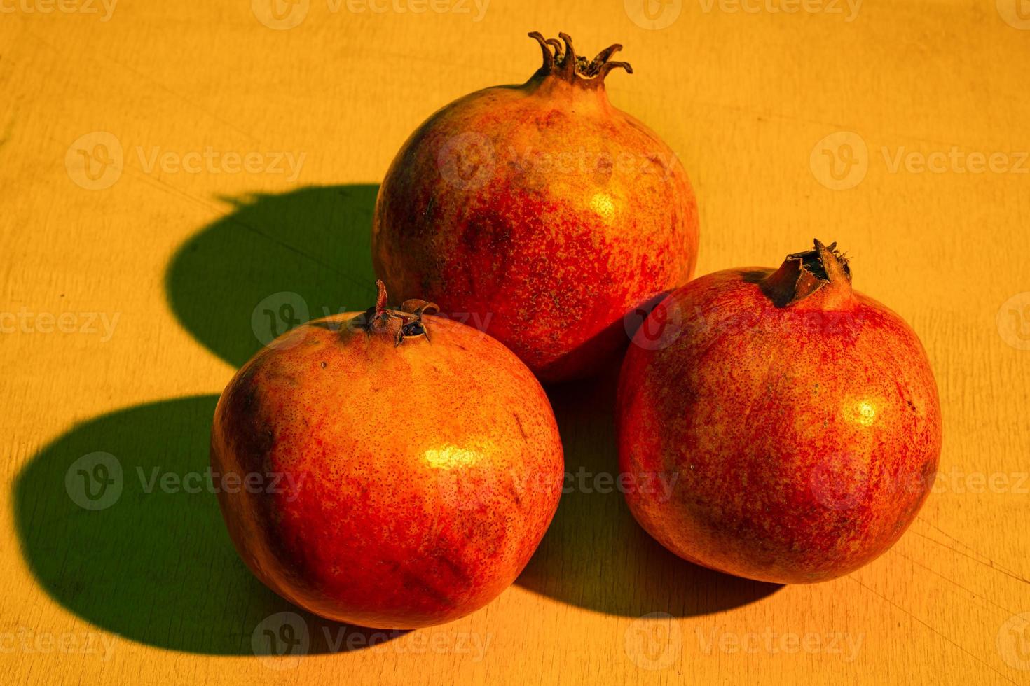 drei reife Granatäpfel auf dem Holztisch foto