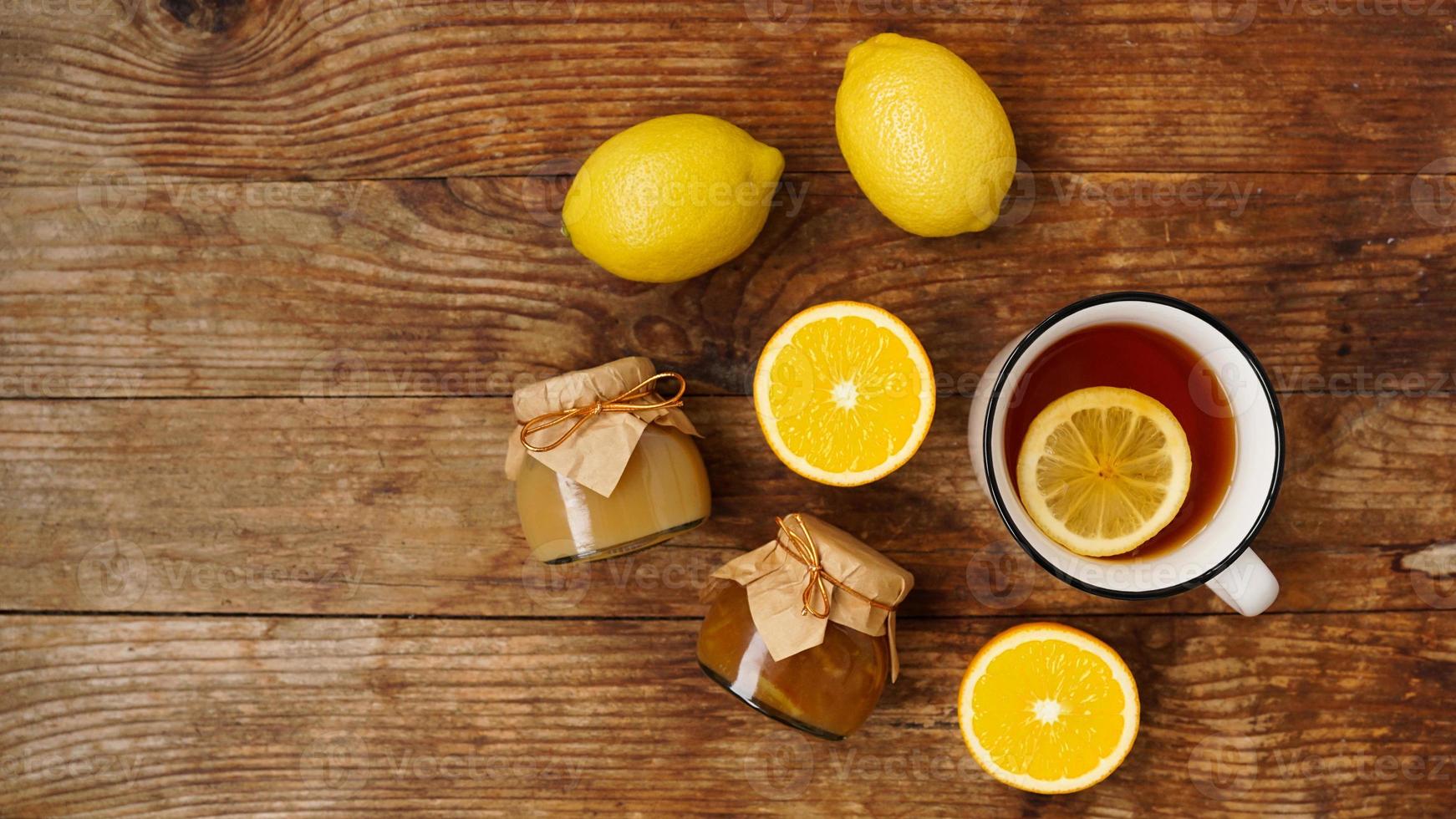 süßes Frühstück. Tasse schwarzer Tee mit Zitrone. Zitronen und Gläser mit Marmelade foto