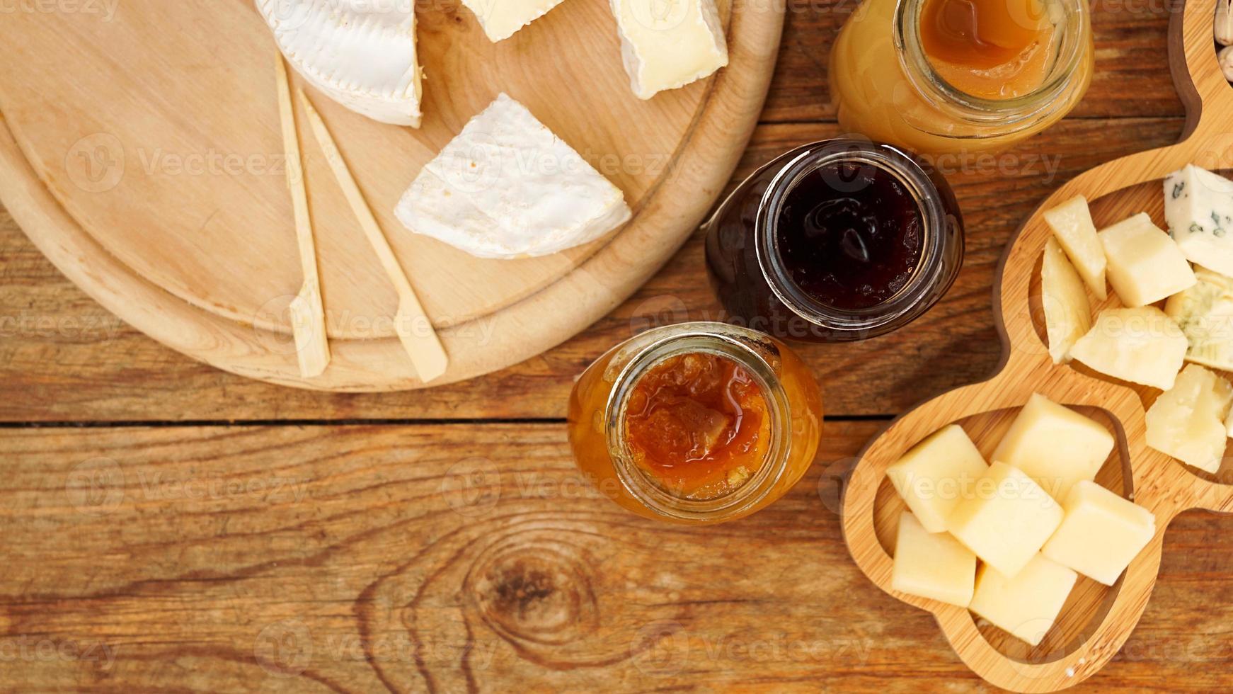 Gläser mit hausgemachten Marmeladen und Honig, Käse auf einem Holztisch. Käseplatte foto