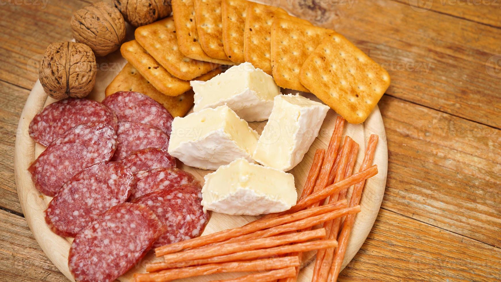 Fleisch- und Käseplatte für Vorspeisen. Wurst, Käse, Cracker, Nüsse auf Holz foto