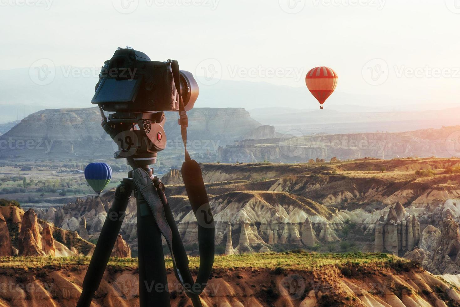 heißluftballon, der über felslandschaft in der türkei fliegt. DSLR-Kamera auf einem Stativ im Vordergrund foto