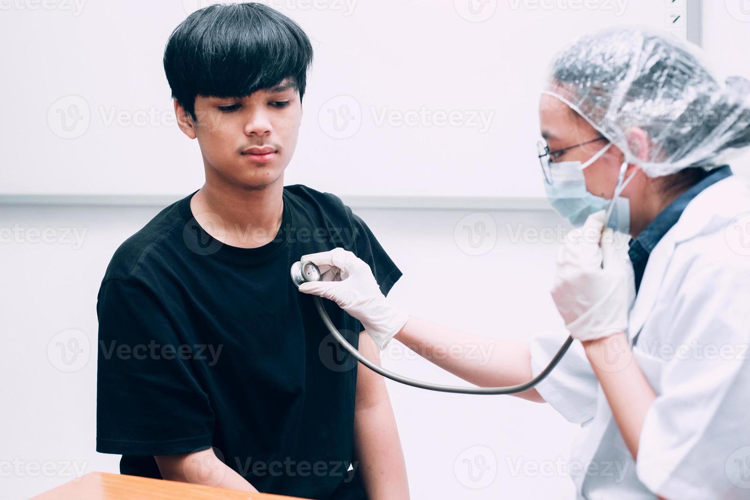 Arzt mit Stethoskop, der die Brust eines Mannes im Krankenhaus überprüft. foto