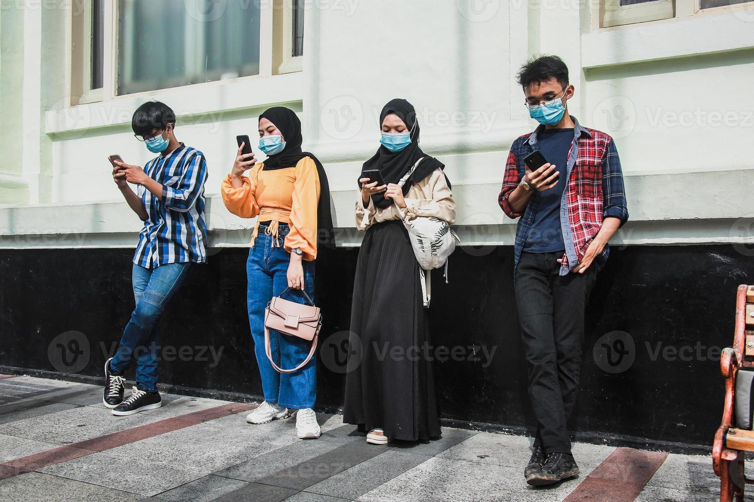 gruppe junger gruppenmenschen, die mobiltelefone verwenden, um inhalte in der neuen normalitätszeit während der coronavirus-pandemie anzusehen. Menschen der tausendjährigen Generation sind immer mit dem Konzept verbunden foto