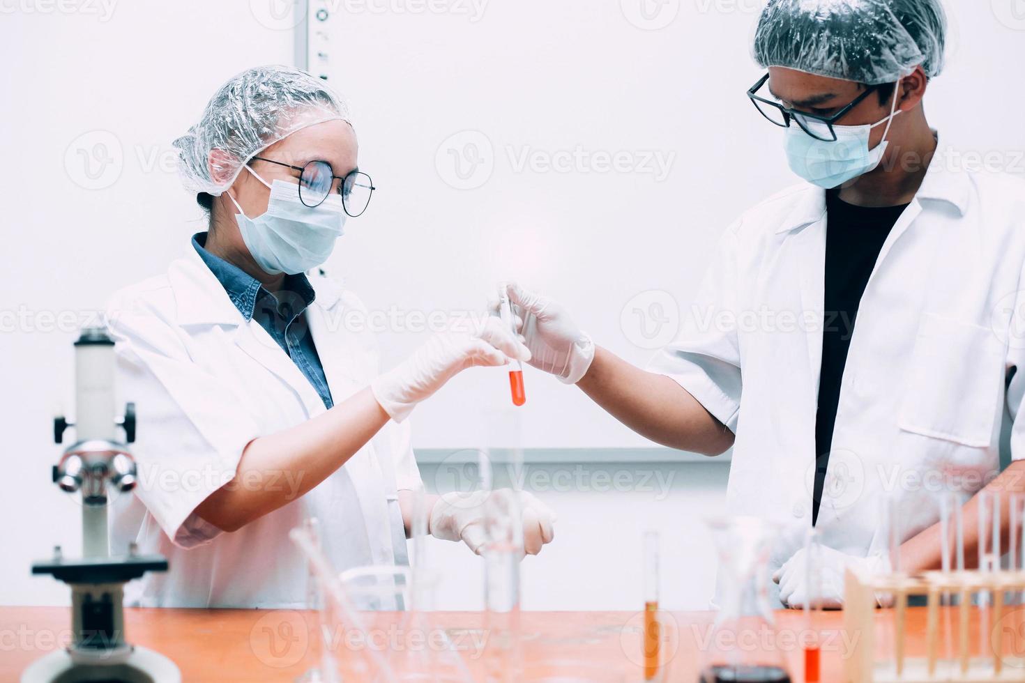 wissenschaftler untersuchen rote flüssigkeit oder probe auf reagenzglas im labor. nationaler wissenschaftstag, weltwissenschaftstag foto