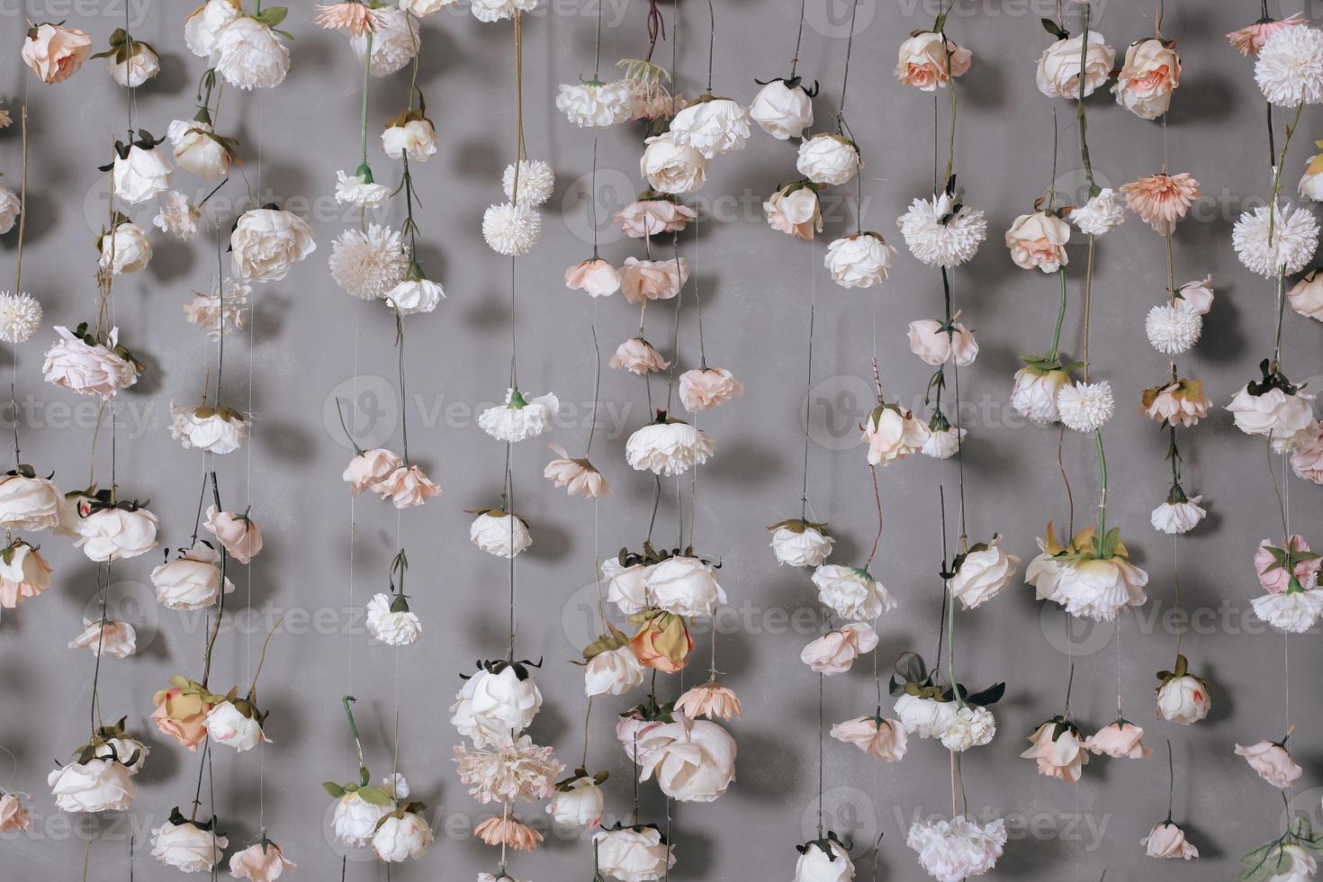 hochzeitsdekoration mit vielen künstlichen blumen, die an der grauen wand hängen. foto