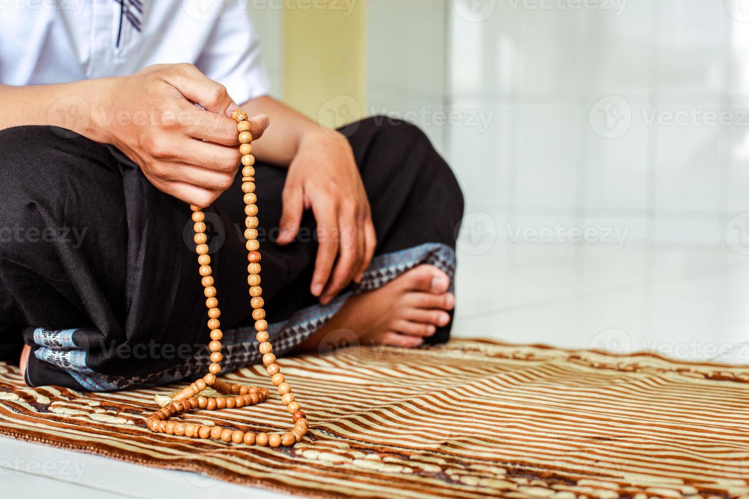 die hand des muslimischen mannes, die rosenkranz hält, um dzikir zu zählen. foto