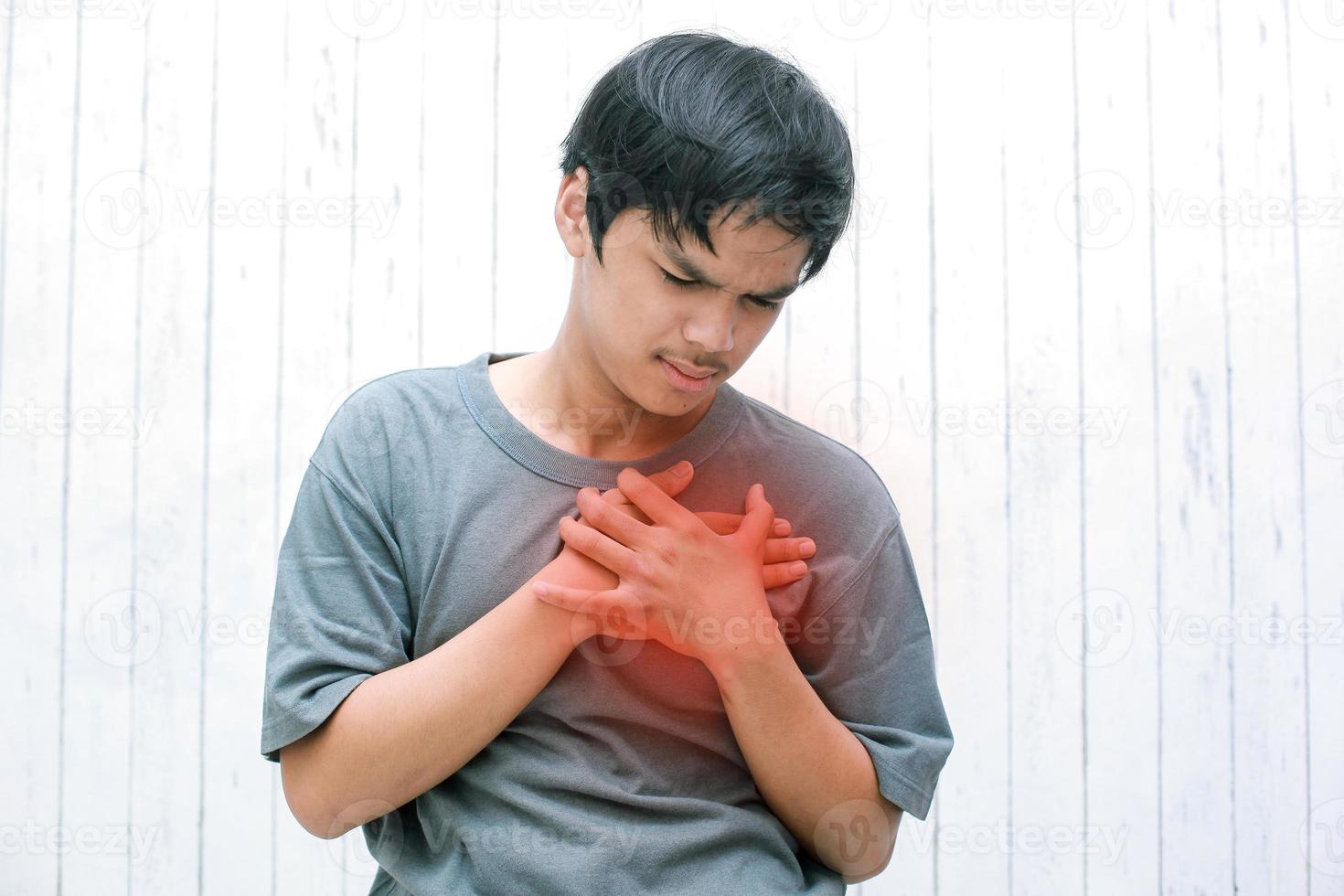 junger Asiate, der seine Brust vor akuten Schmerzen umklammert. Herzinfarkt-Symptom-Gesundheitswesen und medizinisches Konzept. foto