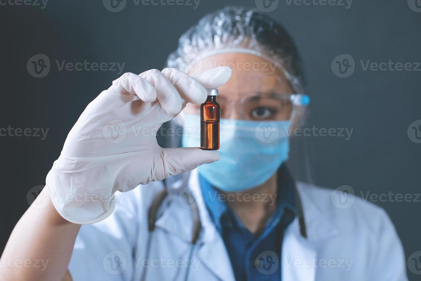 asiatische ärztin oder wissenschaftlerin mit schutzmaske, die eine flasche medikamente in der hand hält. medizin, impfung, immunisierung und gesundheitskonzept foto