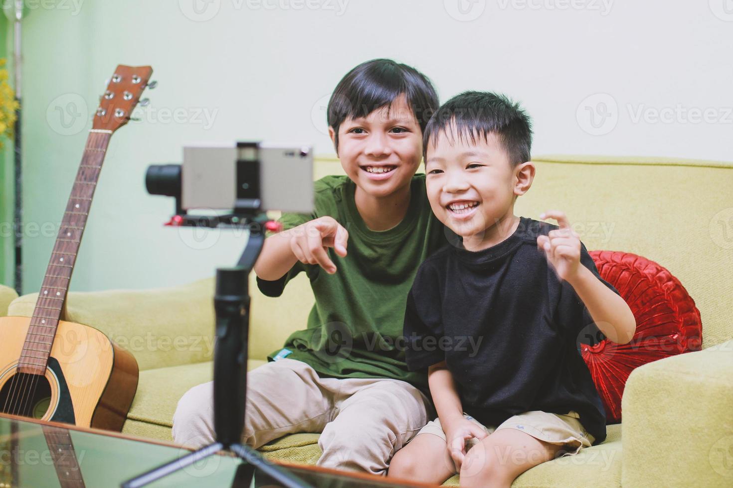 zwei asiatische kinder youtuber lächeln und schauen auf ein smartphone, während sie videoinhalte erstellen foto