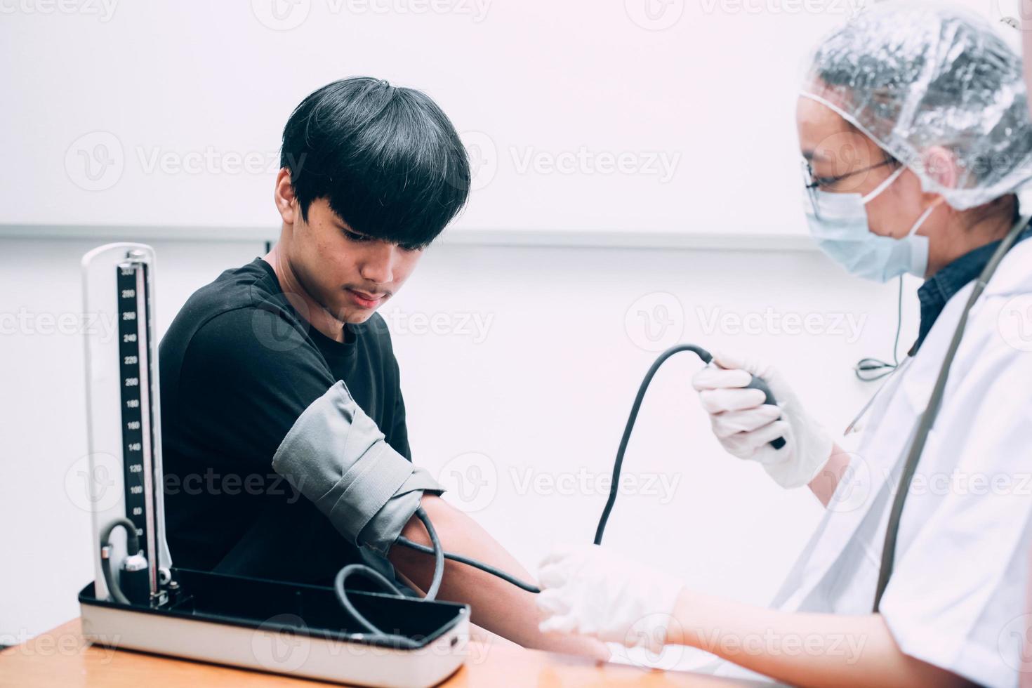 ärztin, die kerlpatient untersucht, der hohen niedrigen arteriellen blutdruck mit medizinischem tonometer im krankenhaus misst. foto