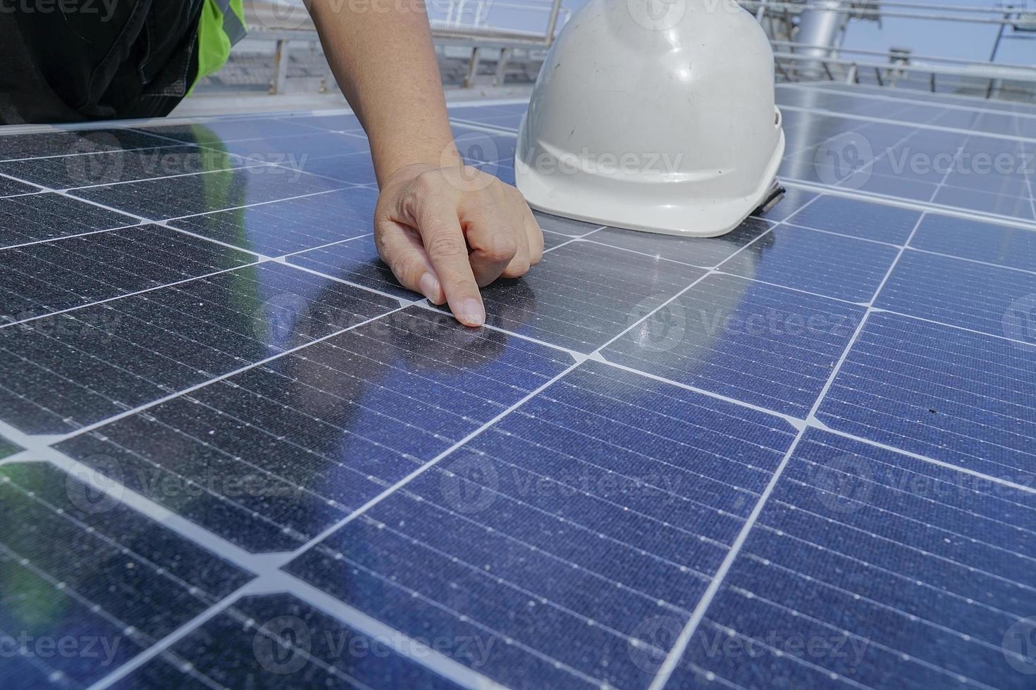 Ein Elektrotechniker mit weißem Hut prüft. Sauberkeit der Sonnenkollektoren auf dem Dach des Gebäudes. foto