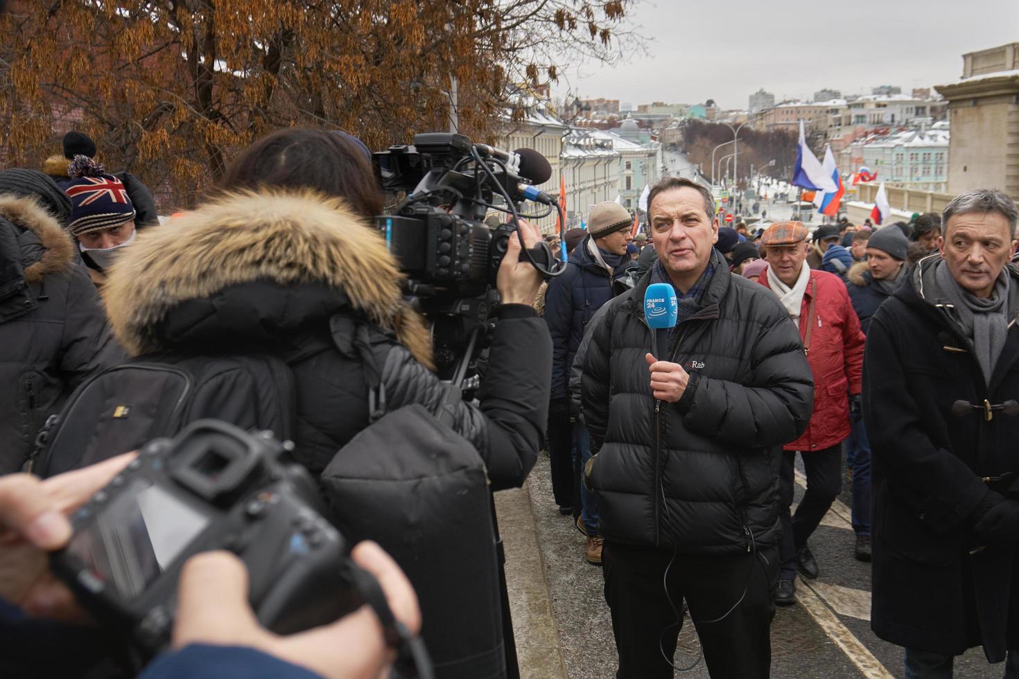 moskau, russland - 24. februar 2019. nemzow-gedenkmarsch. ausländischer Journalist mit Mikrofon berichtet von der Szene zur Digitalkamera foto