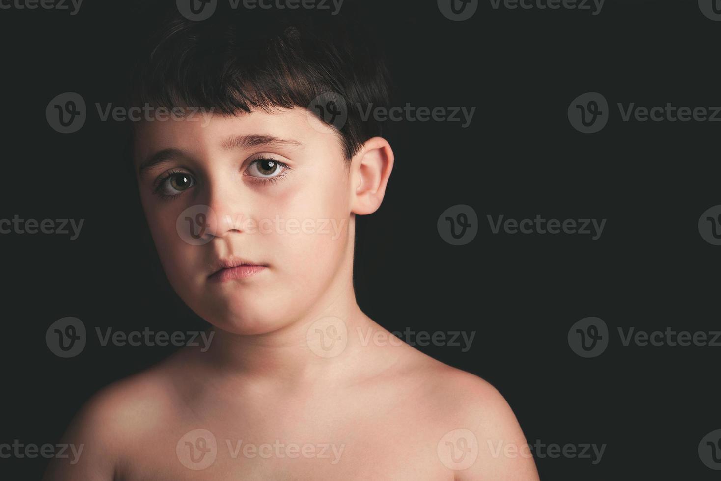 Trauriger Junge auf schwarzem Hintergrund foto