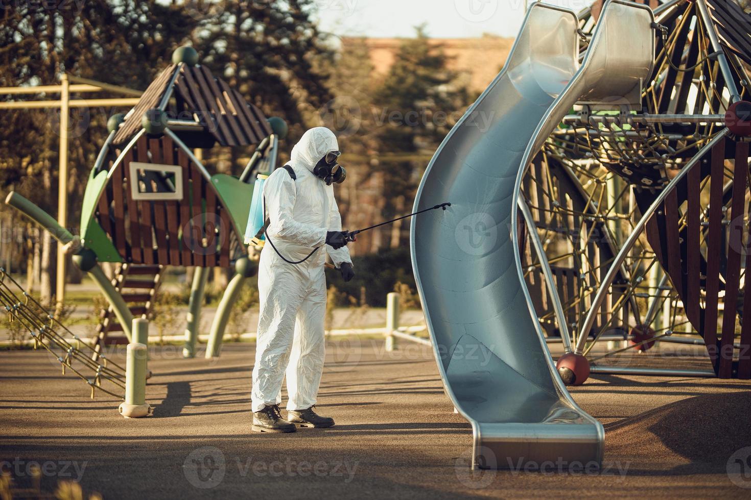 reinigung und desinfektion auf dem spielplatz im stadtkomplex inmitten der coronavirus-epidemieteams zur desinfektionsbemühungen infektionsprävention und bekämpfung von epidemieschutzanzug und maske foto