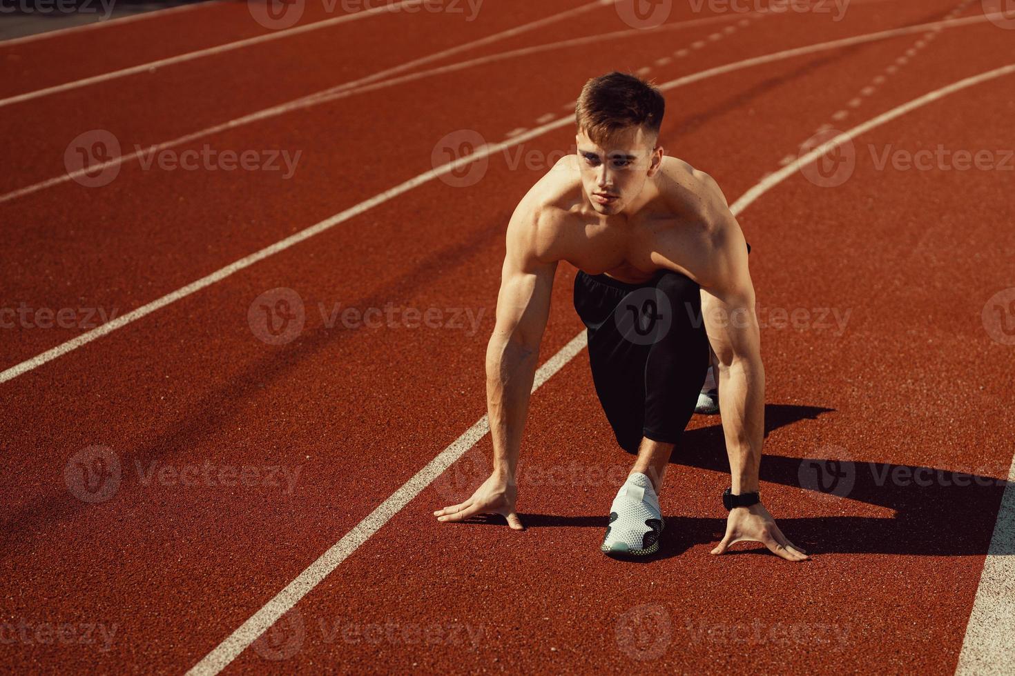 junger Mann mit athletischem Körper, der sich zum Laufen bereit macht foto