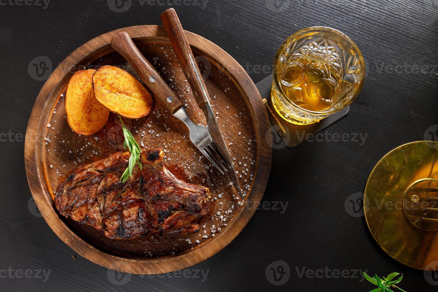 Medium Rare Steak auf Knochen Kalbsrippe mit Kartoffel auf einem Holzteller foto