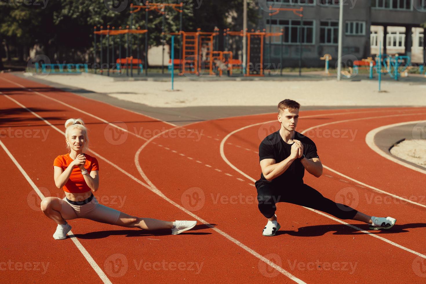 Mädchen und ein Typ, die sich vor Sportübungen im Schulstadion aufwärmen foto