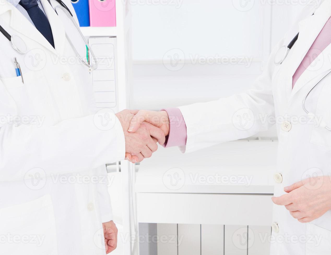 Zwei Ärzte geben sich im Büro die Hand. Krankenversicherung. Gesundheitskonzept. Platz kopieren foto